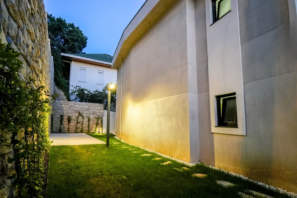 Kartal SRK Villa Yan Bahçe ve Aydınlatma Detayı SRK İnşaat Kartal Villa projesine ait taş duvarlı ve aydınlatmalı yan bahçe alanı
