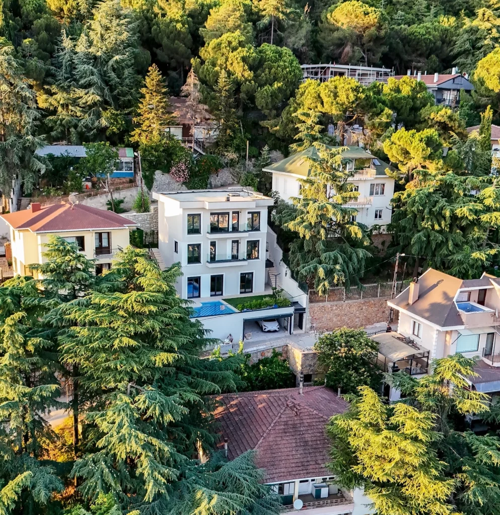 SRK Kartal Villa – Doğa İçinde Havadan Genel Görünüm SRK İnşaat Kartal Villa’nın doğayla çevrili havadan görünümü, havuz ve üç katlı yapı